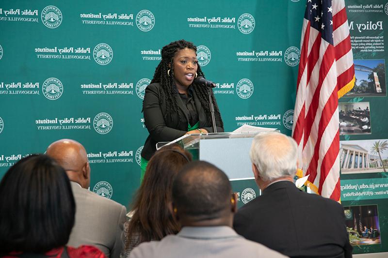 Woman speaking to a crowd at a podium